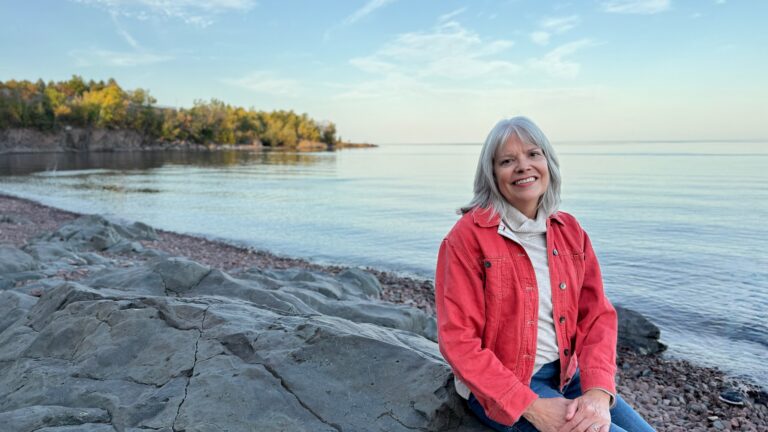 Woman sitting on rock at beach at sunset